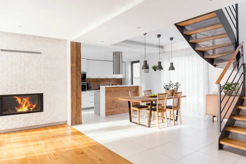 Modern open-plan interior of one of the luxury homes in the luxury real estate in Spring Hill market, featuring a white brick fireplace, rustic wood accents, a sleek designer kitchen, and a contemporary industrial staircase.
